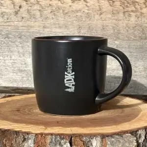 ADKation Life | A dark, modern beverage mug featuring the fun ‘ADK’ and ‘vacation’ word mash up, ‘ADKation’ engraved vertically near the handle. | An emotionally soothing Adirondack vacation gift or souvenir to enjoy at home, the office, or in front of a cozy fire.