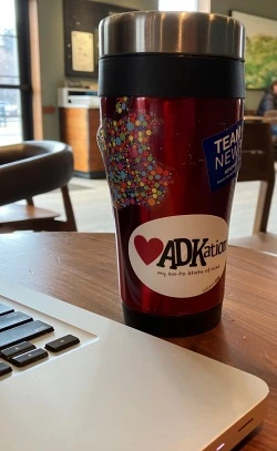 Coffee tumbler with "ADKation" text on a souvenir sticker keeping ADK vacation memories top of mind.